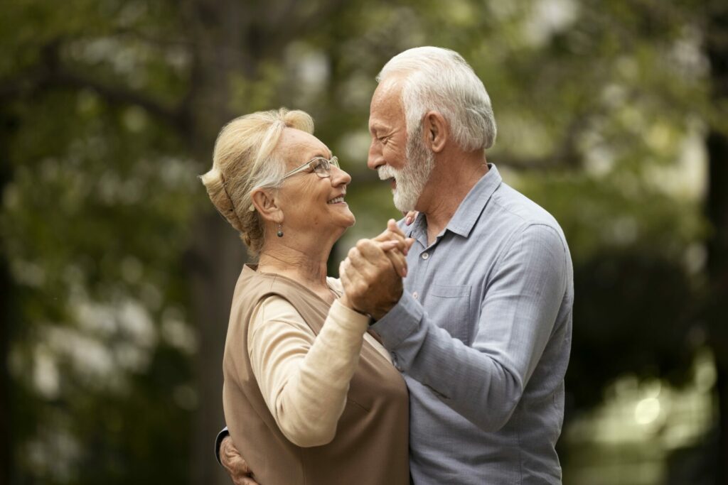 An old couple, dancing lovingly together, outside.
