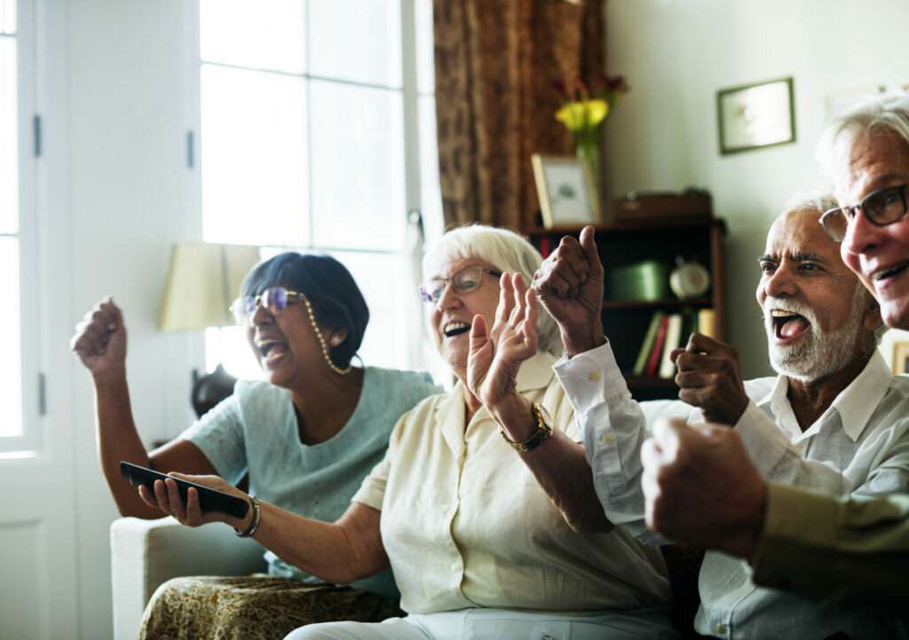 a group of old people sitting on a couch, cheering.