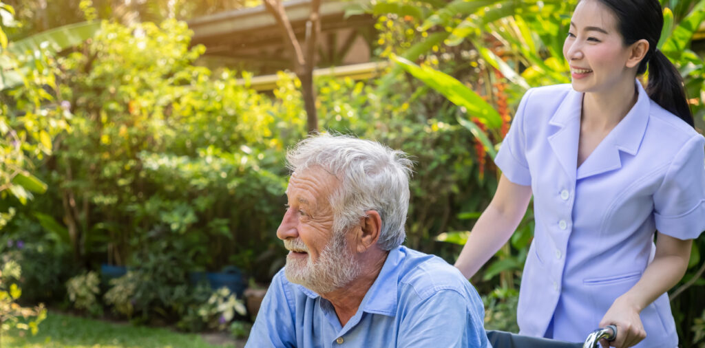 An old man being wheeled around by a nurse.